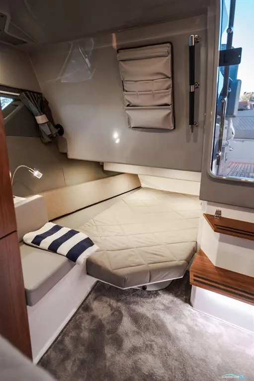 Cosy cabin interior featuring a circular bed, storage pockets, and a stylish light. Soft rug enhances the warm atmosphere.